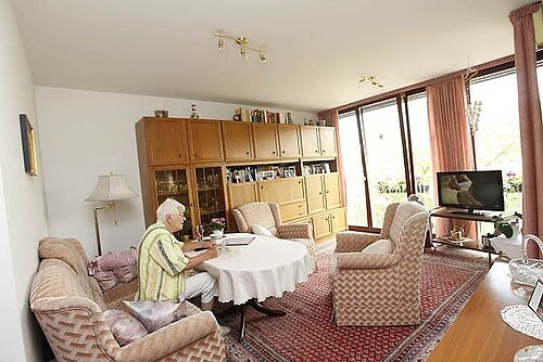Boewohnerin des Betreuten Wohnens in ihrem Wohnzimmer