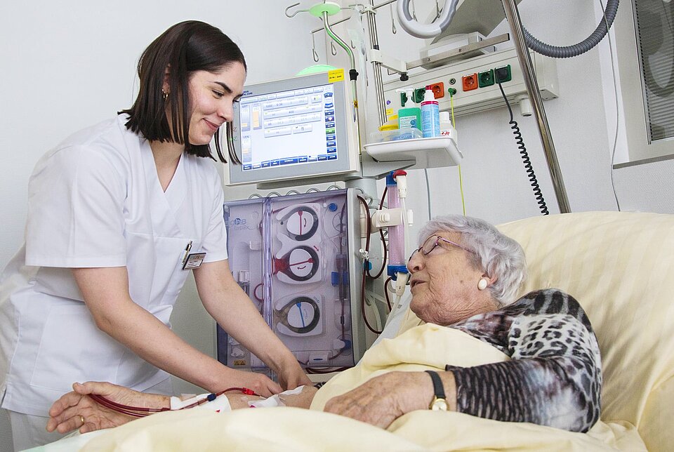 Pflegerin bei älteren Patientin am Bett