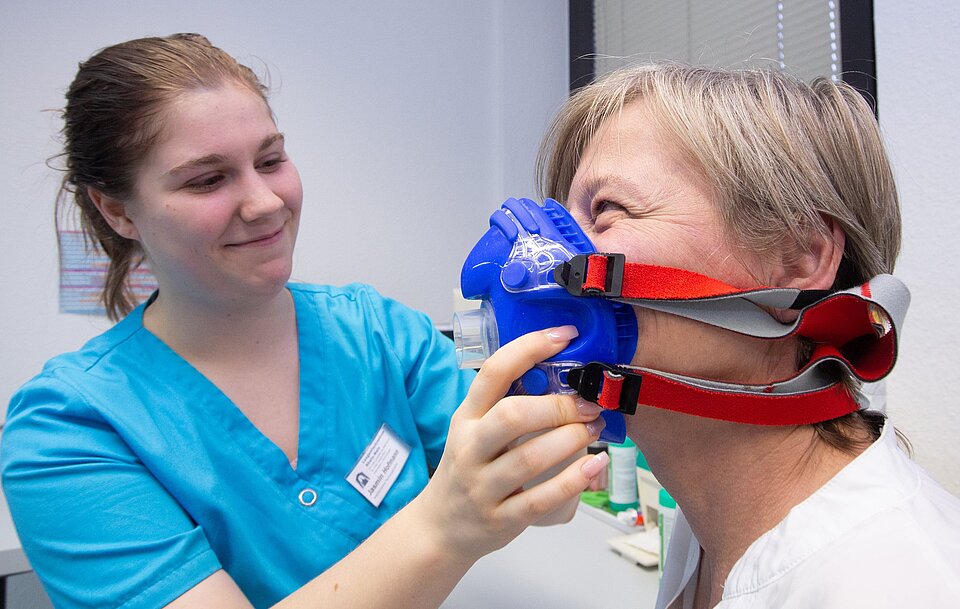 Einer Patientin wird eine Atemmaske aufgesetzt