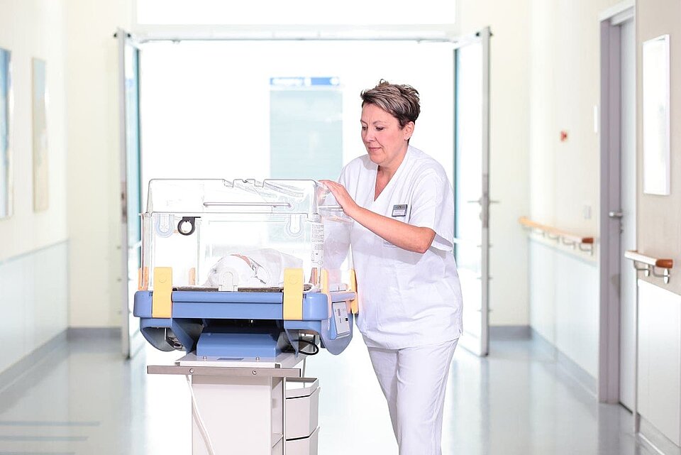 Kinderkrankenschwester mit Wärmetransportbett und Säugling