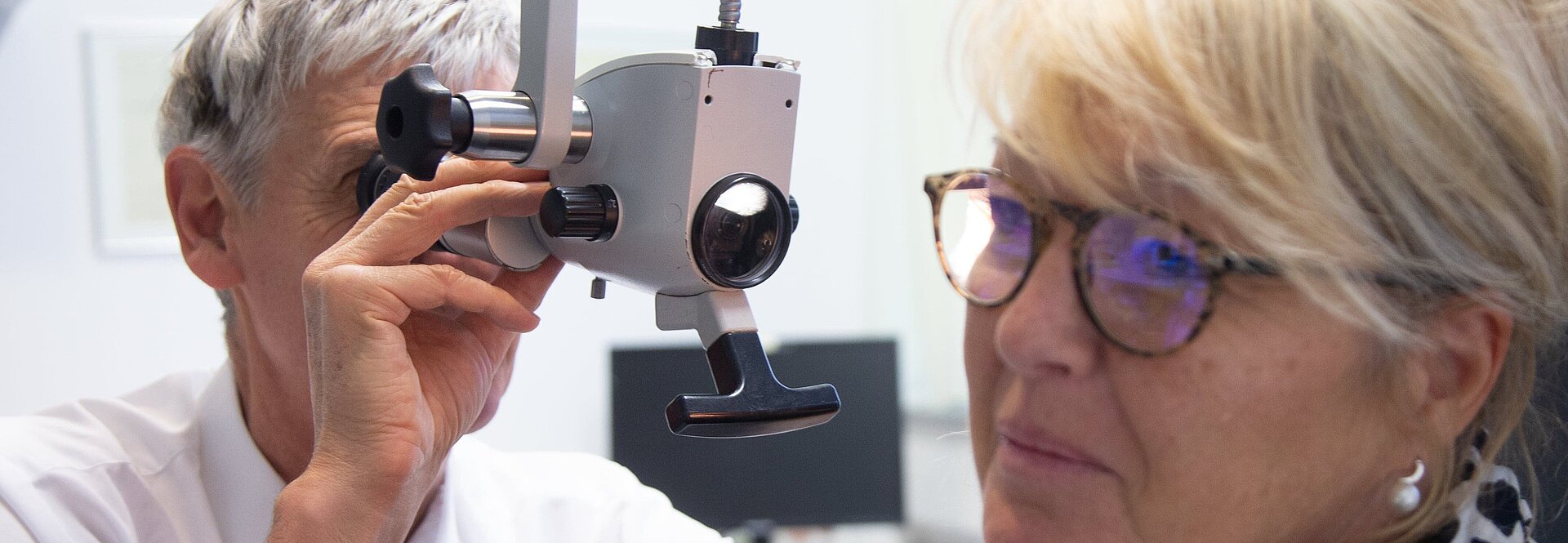 Chefarzt führt Untersuchung am Ohr einer Patientin durch