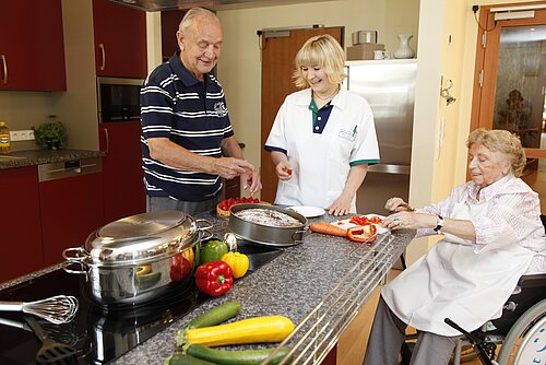 Präsenzkraft und zwei Bewohner beim Kochen