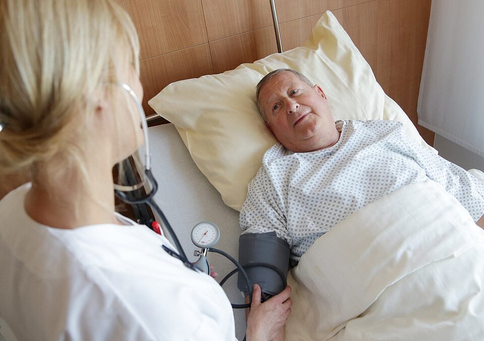 Patient im Krankenbett und Pflegerin