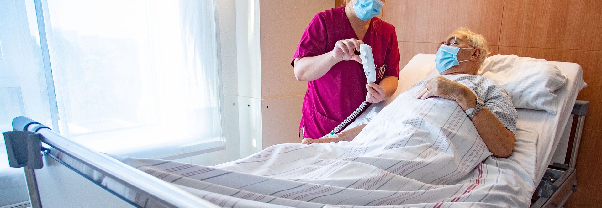 Pflegekraft, die einem Patienten die Funktionen des neuen Bettes erklärt