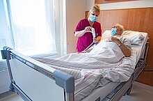 Pflegekraft, die einem Patienten die Funktionen des neuen Bettes erklärt